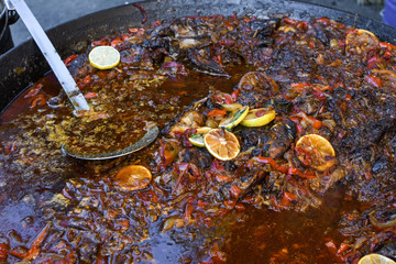 Traditional fish stew being prepared in a rustic bowl over a wood background.