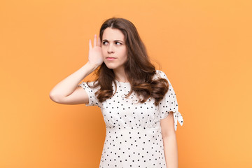 young pretty woman looking serious and curious, listening, trying to hear a secret conversation or...