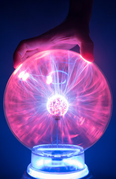 Studio Shot Of Hands On Illuminated Plasma Ball