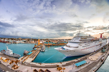 Cruise ship docked at caribbean port. Big ocean liner leaving a port at sunset