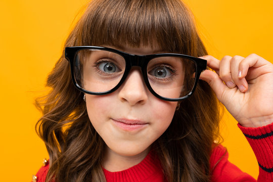 beautiful girl in glasses close-up on an orange studio background