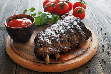 Grilled and smoked ribs with tomato sauce on a round wooden board