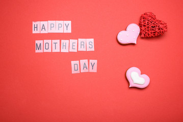 Red background with the inscription Mother's Day, gingerbread in the form of hearts. Holiday content.