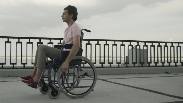 Man with paralysis of legs muscles is sitting in invalid carriage and riding. Ride from Left to Right