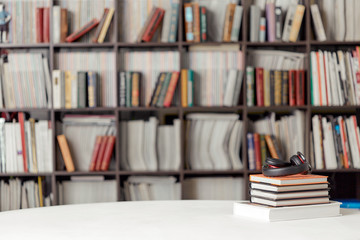 A stack of books with headphones on the background of a rack of books in the reading room of the library. Student poster