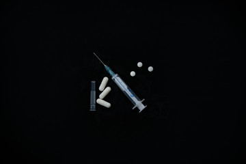 syringe and pills on a black background