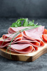 Close up ham slices isolated on cutting board over dark background.