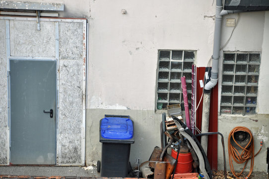 Blick in Hinterhof mit M&uuml;lltonne und Sperrm&uuml;ll an einer Hauswand mit Stahlt&uuml;re 