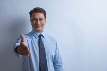Portrait of a smiling businessman extending his arm to shake hands
