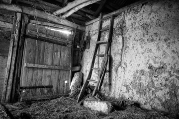 Fototapeta na wymiar Old abandoned barn in the village. Inside the retro staircase leads to the attic. Horizontal frame. Black and white image, sepia. Photographed in Ukraine. Kiev region.