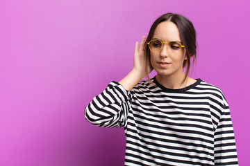 young pretty woman looking serious and curious, listening, trying to hear a secret conversation or...