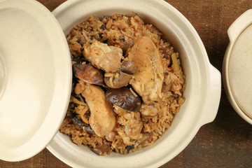 Clay pot chicken rice with mushroom in clay ceramic bowl on rustic wood table background