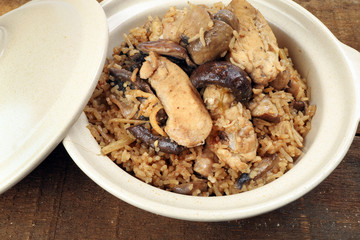 Clay pot chicken rice with mushroom in clay ceramic bowl on rustic wood table background