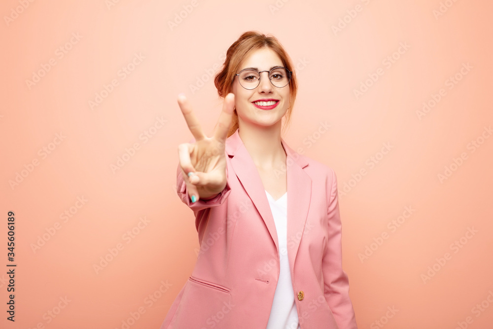 Wall mural young pretty blonde woman smiling and looking friendly, showing number two or second with hand forwa