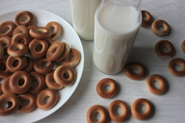 Milk in bottles and small dry bagels for kids on white wooden background. First solid finger food for baby
