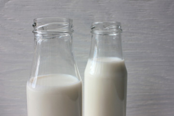 Milk in small bottles on white wooden background. Healthy organic beverage. 