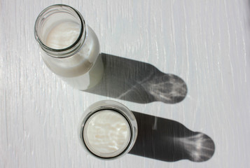 Milk in small bottles on white wooden background. Healthy organic beverage. Top view. Copy space
