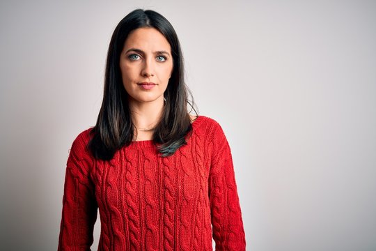 Young brunette woman with blue eyes wearing casual sweater over isolated white background Relaxed with serious expression on face. Simple and natural looking at the camera.