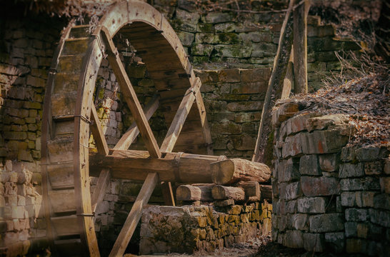 Summer day. In the frame of the old water mill. A huge wooden wheel made of wood. Photographed in Ukraine. Kiev region. Horizontal frame. Color image.