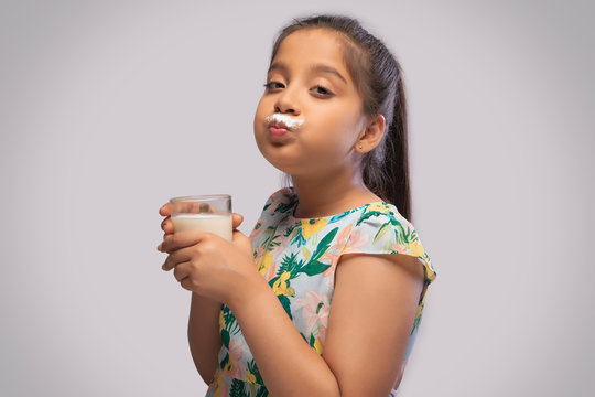Side view of a girl having milk moustache drinking milk in a glass
