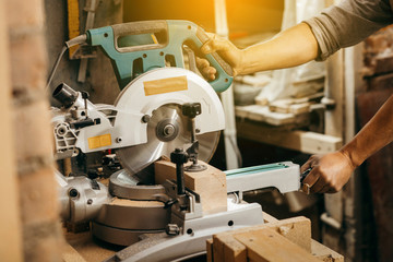 Carpenter using a circular cut off saw to trim wood studs length.