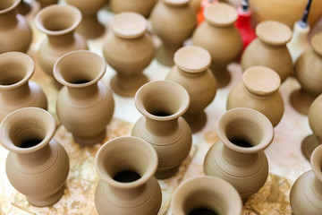 Pitchers brown clay pottery are on the table in the pottery workshop