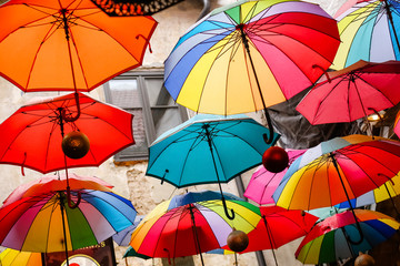 Many bright colored outdoor umbrellas are hanging