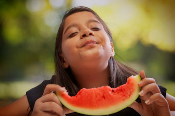 Girl eating a watermelon enjoying its taste with closed eyes
