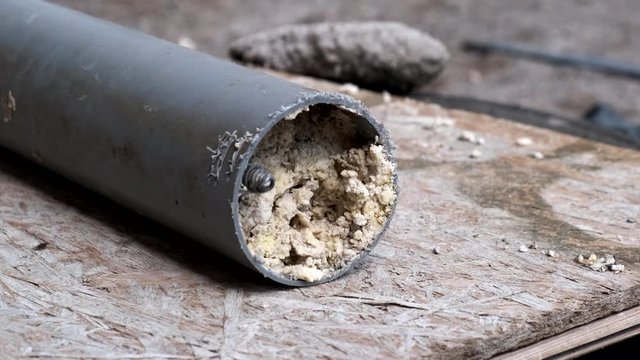 Сlean a clogged sewer pipe. A plumber shows how to clean a clogged sewer pipe using cleaning tool. Close-up.