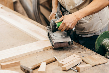Worker grinds the wood of angular grinding machine