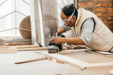Worker grinds the wood of angular grinding machine