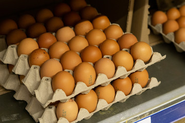 Fresh chicken brown eggs in a cardboard egg tray on a shelf in a store