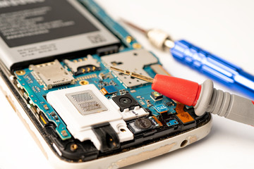 Mainboard circuit inside of mobile phone with voltage tester.