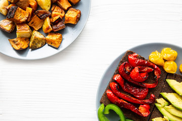 Roasted sweet potatoes (batata) and grilled paprika and avocado healthy sandwiches on white background.