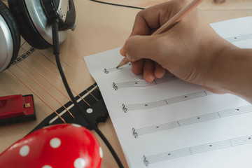 Music instruments concept background. Close up musician writing note on the paper for create song...