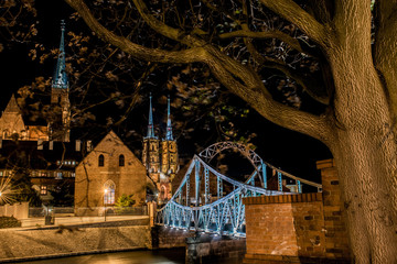 Fototapeta premium Wroclaw by night. View of cathedral, river, lovers bridge and Ostrow Tumski district. Historic architecture, gothic style. Lamps, flares, light. Cityscape shot in Poland.