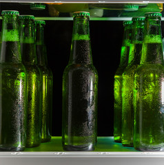 Green beer bottles on the shelf in the refrigerator. The fog on the glass.