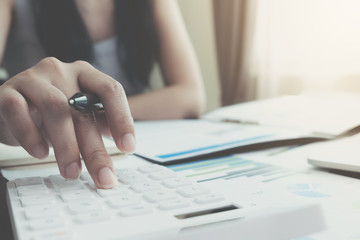 Close up Businesswoman using calculator and laptop for do math finance on wooden desk in office and business working background, tax, accounting, statistics and analytic research concept