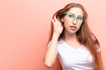 yound blonde woman looking serious and curious, listening, trying to hear a secret conversation or...