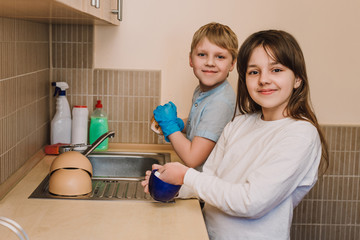 Beautiful girl and a young boy helps them mom perform a housework. Beautiful girl and a young boy helping with the washing up after breakfast before school