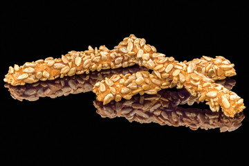 Tasty breadsticks grissini with sunflowers seeds with reflection, isolated on black background.