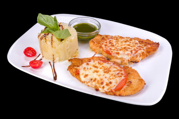 Tasty fried chicken with tomato and parmesan served with sauce and mashed potatoes, isolated on black background