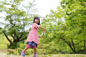 春の公園でシャボン玉を遊んでいる可愛い子供