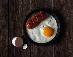 fried egg and sausage in a frying pan on the table shell
