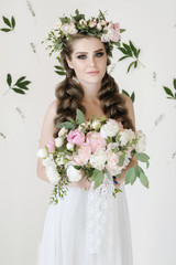 The bride holds a wedding bouquet, wedding dress, wedding details. wedding bouquet of peonies. Bride with snatural wreath of fresh flowers. Hairstyle from volumetric braids. lifestyle, fashion
