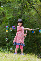 春の公園でシャボン玉を遊んでいる可愛い子供