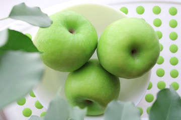 three apples under the branches of green