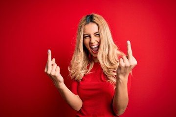 Young beautiful blonde woman wearing casual t-shirt standing over isolated red background Showing...