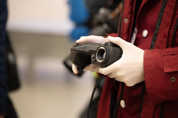 man in protective gloves checks the temperature with a thermal imager in a public place. protective measures against the spread of infection.