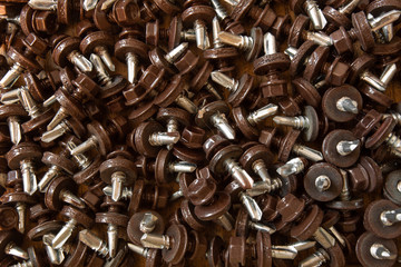 A lot of brown metal screws on the table close-up, background